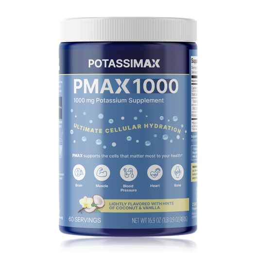 A tub of Potassium Max 1000 dietary supplement on a plain white background. The container is dark blue with a white ribbed cap and a blue label featuring white and yellow text, along with small illustrations of fruit and flowers indicating a lightly flavored coconut and vanilla taste.